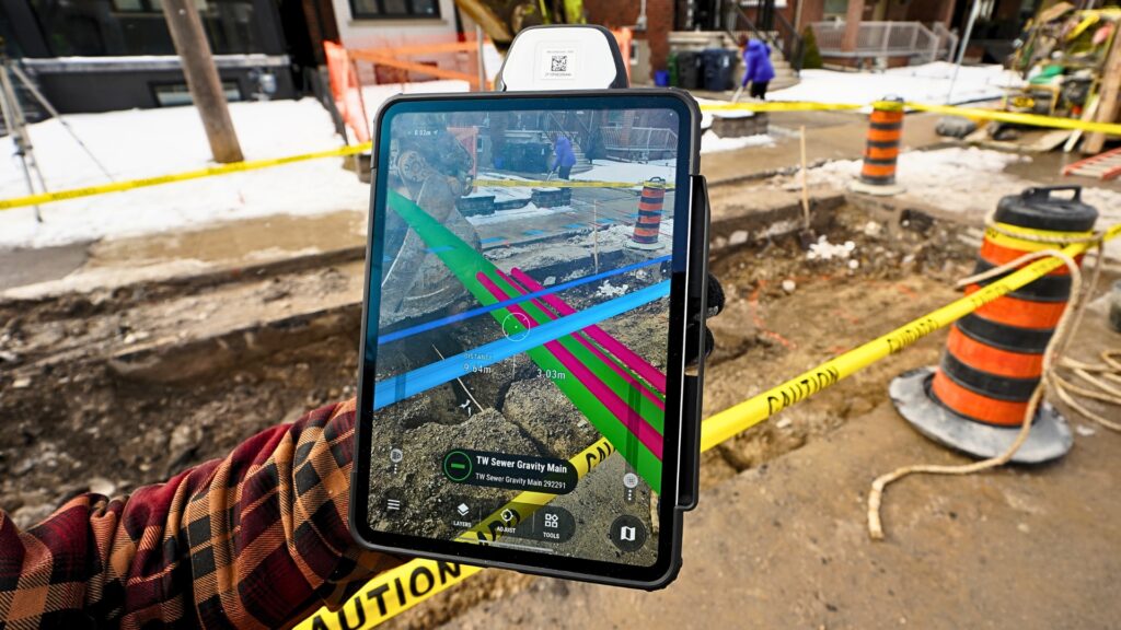 Tablet displaying vSite augmented reality visualization of underground utility lines at a Toronto construction site